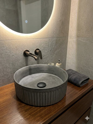 Gray ceramic sink on a wooden vanity with a round mirror above. concrete basin 